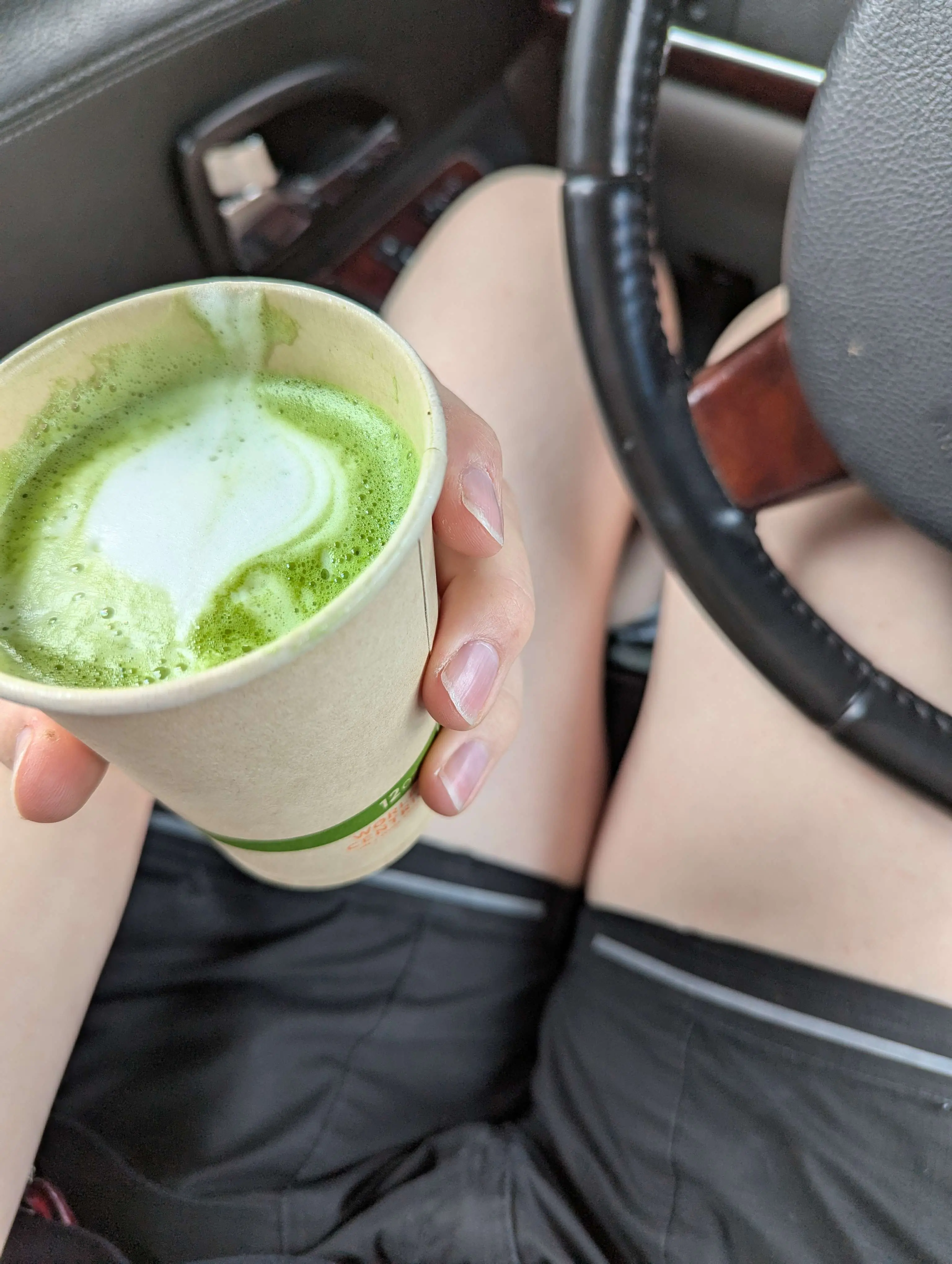 Gen holding matcha latte in her car that she was also sleeping in for fun