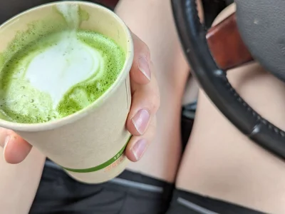 Gen holding matcha latte in her car that she was also sleeping in for fun